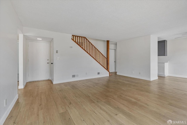 unfurnished living room with a textured ceiling and light hardwood / wood-style flooring