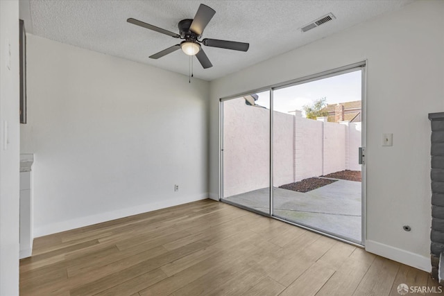 empty room with a textured ceiling, ceiling fan, and wood-type flooring