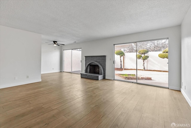 unfurnished living room with ceiling fan, a textured ceiling, light hardwood / wood-style flooring, and a fireplace