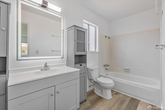 full bathroom with toilet, tiled shower / bath, vanity, and hardwood / wood-style floors