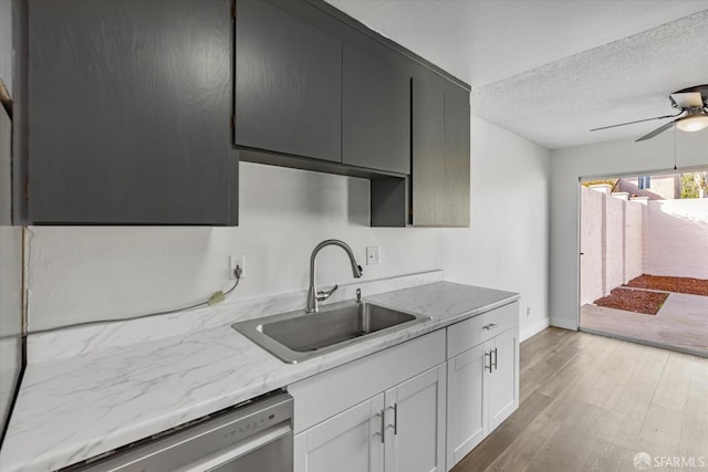 kitchen featuring a textured ceiling, white cabinetry, light hardwood / wood-style floors, sink, and stainless steel dishwasher