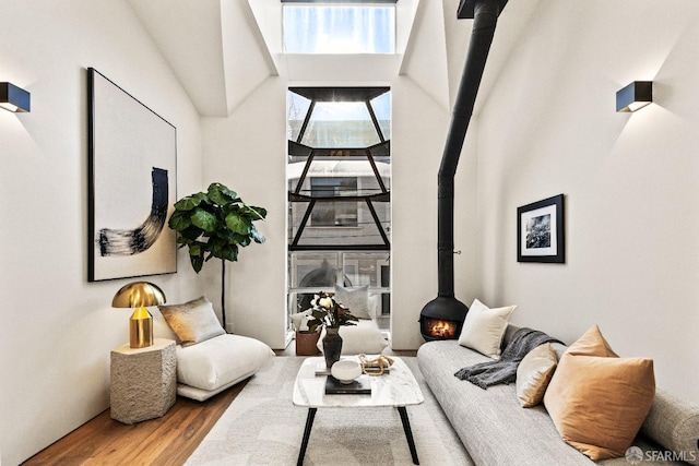 living room featuring a wood stove, a towering ceiling, and wood finished floors