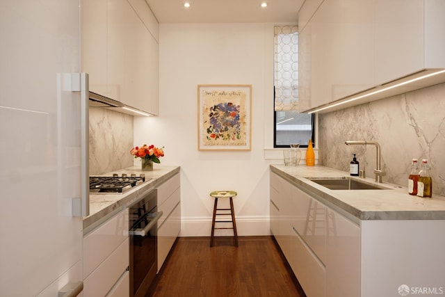 kitchen with dark wood finished floors, stainless steel appliances, light countertops, white cabinets, and a sink