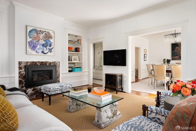 living room featuring a fireplace, built in features, crown molding, and wood finished floors