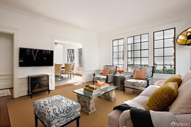 living area with crown molding, wainscoting, a fireplace, and a decorative wall