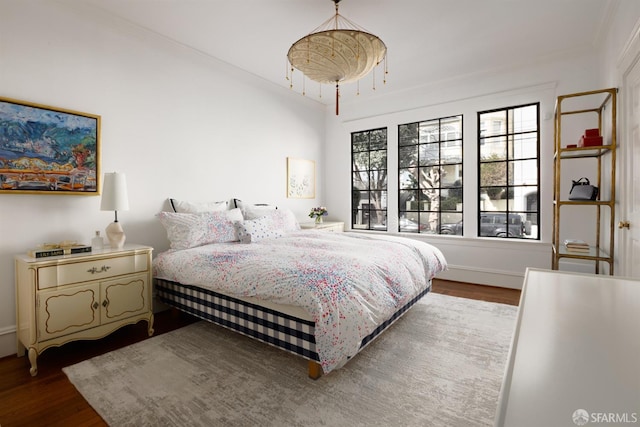 bedroom with ornamental molding, dark wood finished floors, and baseboards