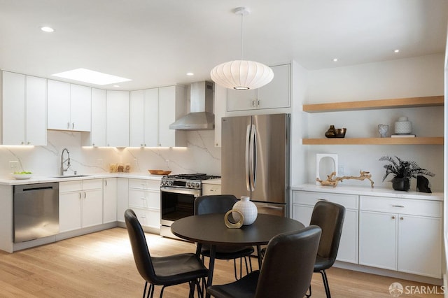 69 Lobos St, San Francisco, CA 94112 - kitchen with appliances with stainless steel finishes, wall chimney exhaust hood, a skylight, decorative backsplash, and recessed lighting