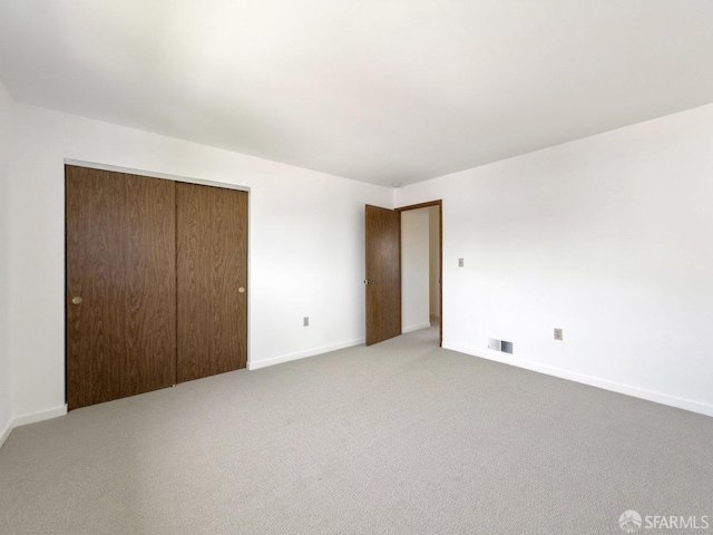 unfurnished bedroom featuring baseboards, a closet, visible vents, and carpet floors