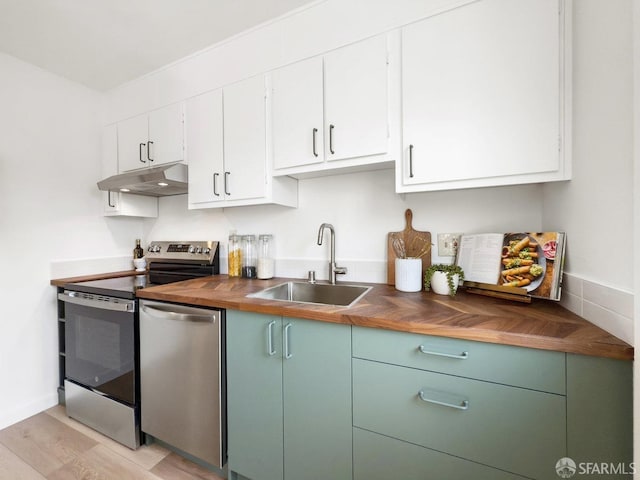 kitchen with a sink, stainless steel appliances, butcher block counters, under cabinet range hood, and white cabinetry