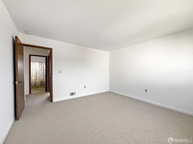 empty room featuring light carpet, baseboards, and visible vents