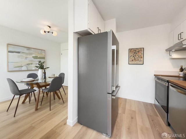 kitchen with light wood finished floors, white cabinets, appliances with stainless steel finishes, and under cabinet range hood