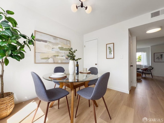 dining room featuring baseboards, visible vents, and light wood-style floors
