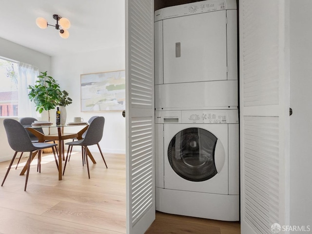 laundry area featuring light wood-style floors, laundry area, and stacked washer / dryer