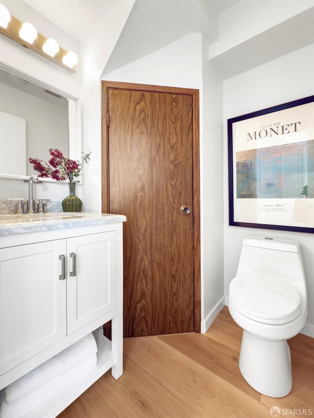 bathroom featuring toilet, wood finished floors, visible vents, baseboards, and vanity