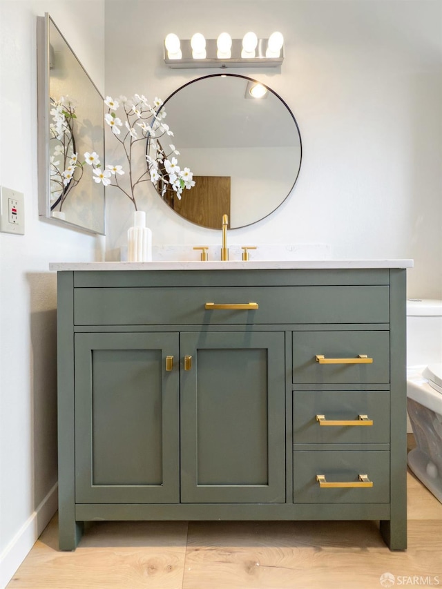 bathroom featuring toilet, baseboards, vanity, and wood finished floors