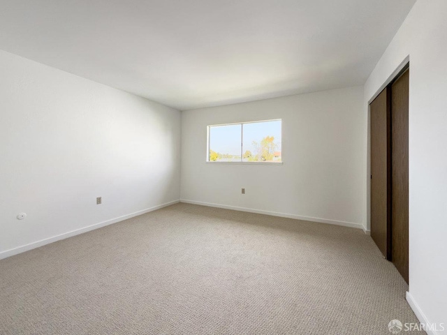 unfurnished bedroom featuring light carpet, a closet, and baseboards