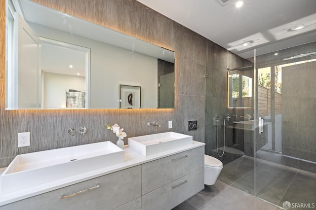 bathroom featuring tile patterned floors, toilet, tile walls, vanity, and a shower with door