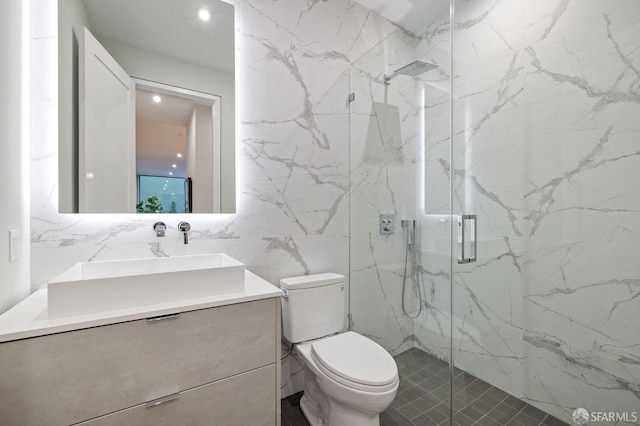 bathroom with vanity, a shower with shower door, tile walls, and toilet