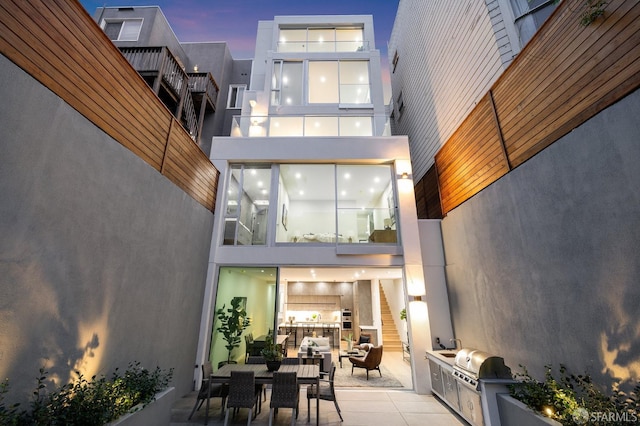 back house at dusk with a patio and area for grilling