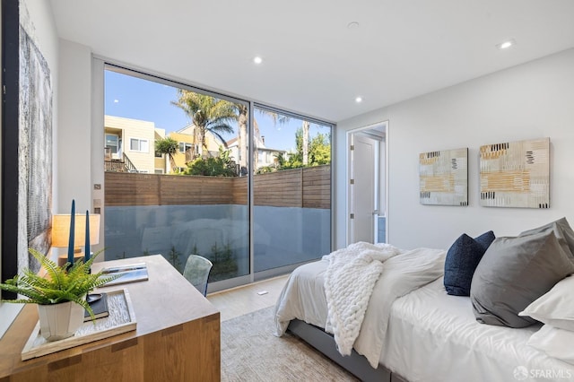 bedroom with expansive windows, access to outside, and light hardwood / wood-style flooring