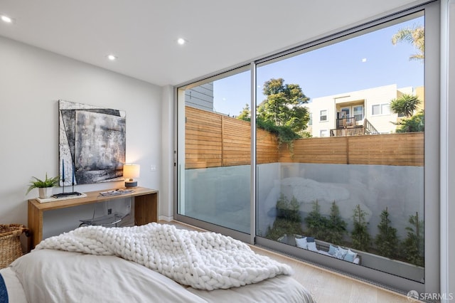 bedroom with access to exterior, hardwood / wood-style floors, and expansive windows