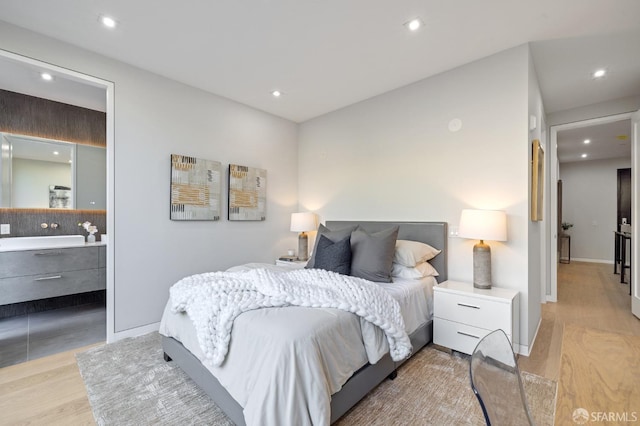 bedroom with connected bathroom and light hardwood / wood-style flooring