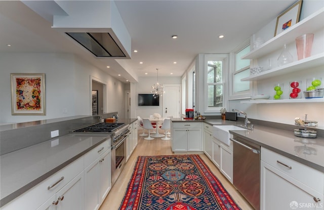 kitchen featuring stainless steel appliances, a sink, light wood-type flooring, a chandelier, and white cabinetry