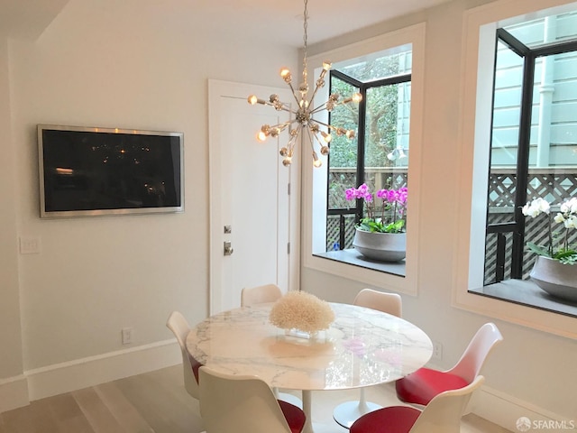 dining area featuring wood finished floors, baseboards, and a notable chandelier
