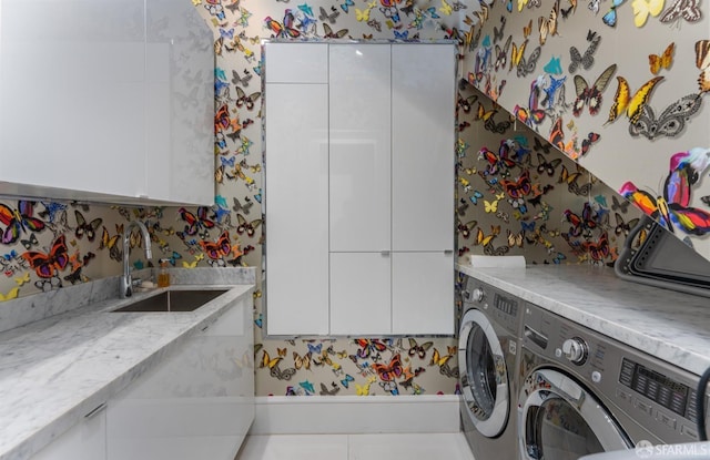 laundry room featuring separate washer and dryer, cabinet space, a sink, and wallpapered walls