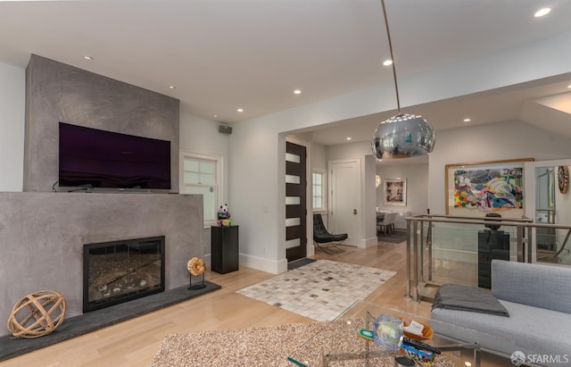 living area with recessed lighting, a high end fireplace, wood finished floors, and baseboards