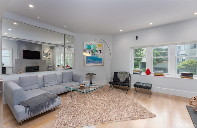 living room featuring a fireplace, baseboards, wood finished floors, and recessed lighting