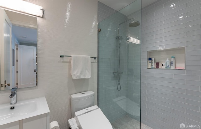 bathroom with toilet, walk in shower, vanity, and tile walls