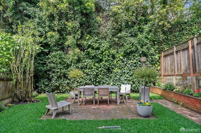 view of yard with a fenced backyard, outdoor dining area, and a patio