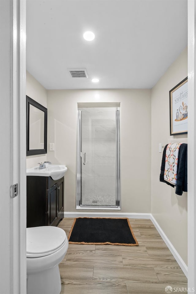 bathroom with hardwood / wood-style flooring, vanity, walk in shower, and toilet