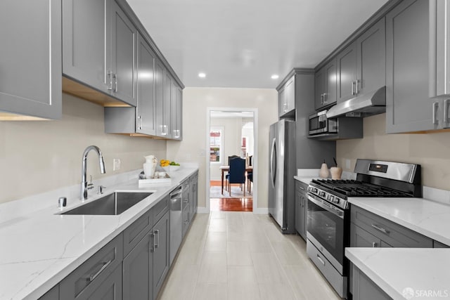 kitchen featuring light stone counters, sink, gray cabinets, and stainless steel appliances