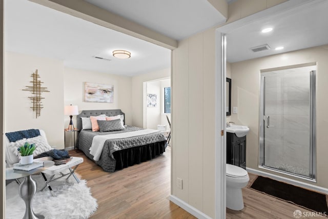 bedroom with sink, ensuite bathroom, and light wood-type flooring