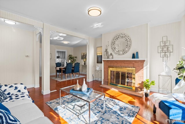 living room featuring decorative columns, dark wood-type flooring, and a fireplace