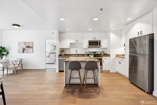 kitchen featuring a center island, dark stone counters, white cabinetry, and appliances with stainless steel finishes