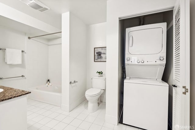 full bathroom featuring toilet, tile patterned floors, vanity, washtub / shower combination, and stacked washing maching and dryer