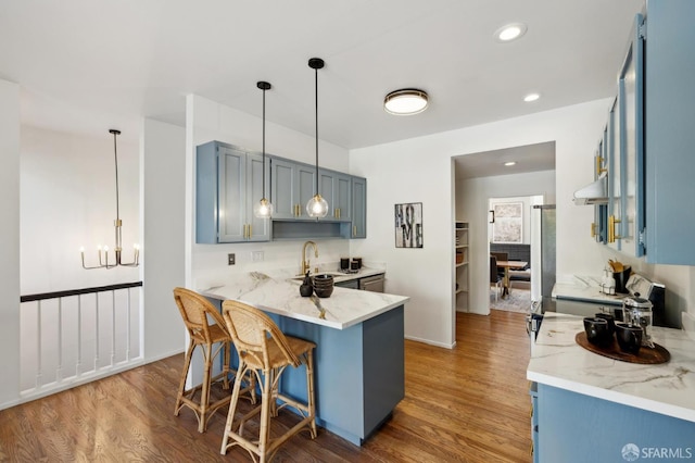 112 S Lake Merced Hls, San Francisco, CA 94132 - kitchen with under cabinet range hood, a sink, wood finished floors, blue cabinets, and a peninsula
