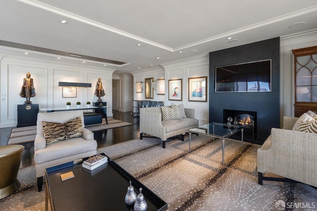 living room featuring a large fireplace, a raised ceiling, crown molding, and decorative columns