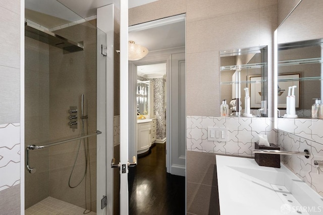 bathroom featuring vanity, a shower with shower door, and decorative backsplash