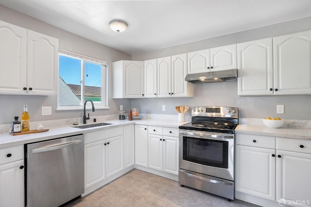 kitchen with white cabinets, stainless steel appliances, light countertops, under cabinet range hood, and a sink