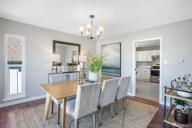 dining area featuring baseboards, a notable chandelier, and wood finished floors