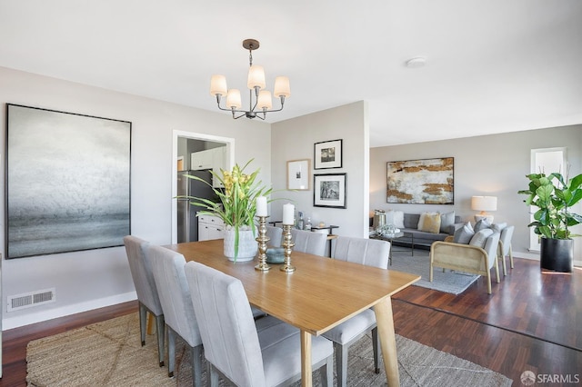 dining area featuring baseboards, wood finished floors, visible vents, and an inviting chandelier