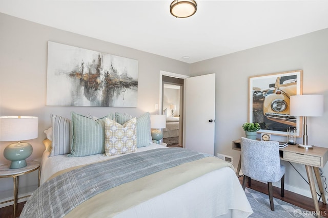 bedroom with a baseboard heating unit, visible vents, baseboards, and wood finished floors