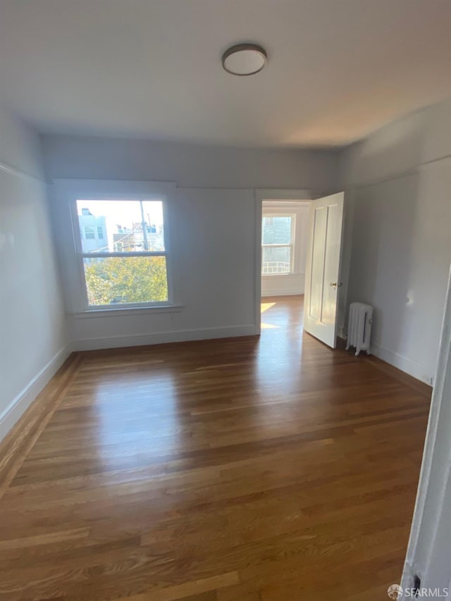 spare room with radiator and dark hardwood / wood-style floors