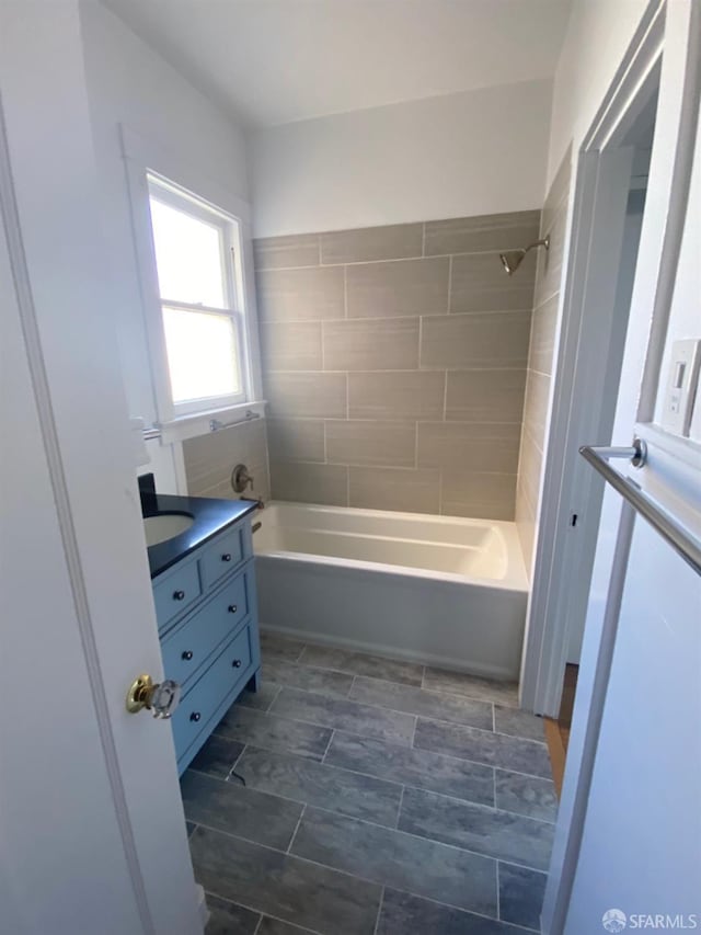 bathroom featuring tiled shower / bath combo and vanity