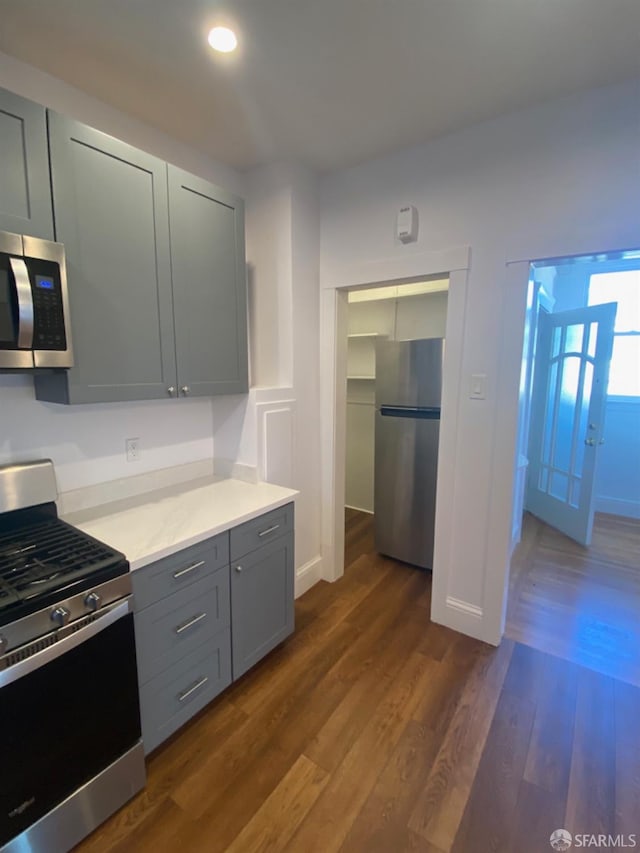 kitchen with gray cabinetry, dark hardwood / wood-style flooring, and appliances with stainless steel finishes