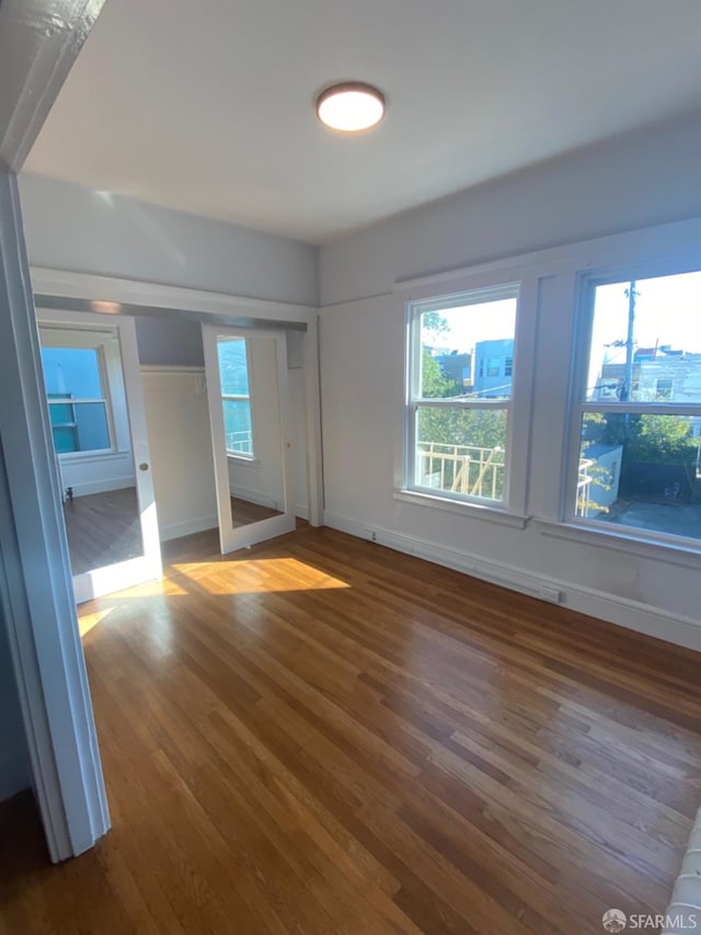 unfurnished bedroom with multiple windows and dark hardwood / wood-style flooring